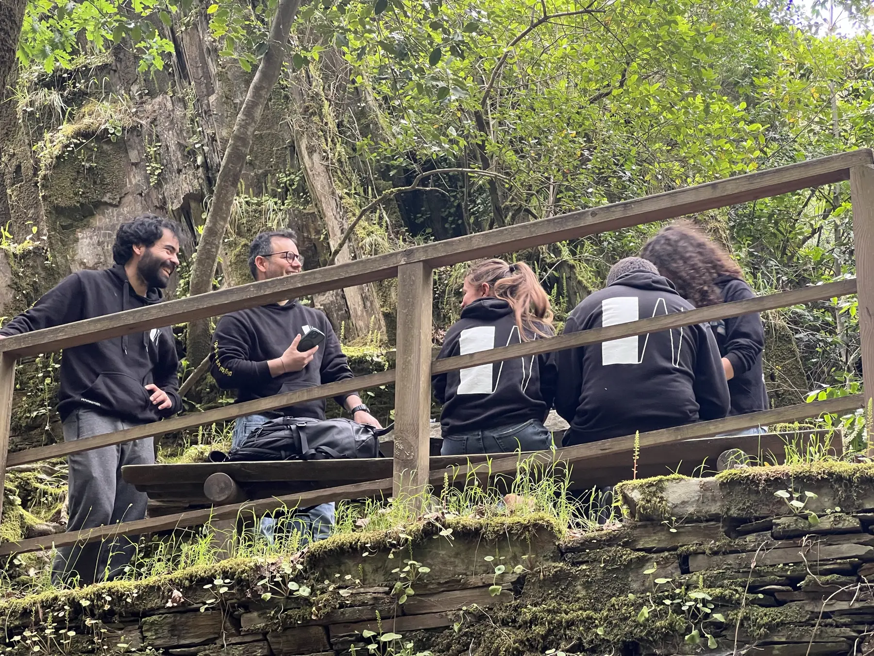 Whitesmith team talking on a wooden bridge during a hike