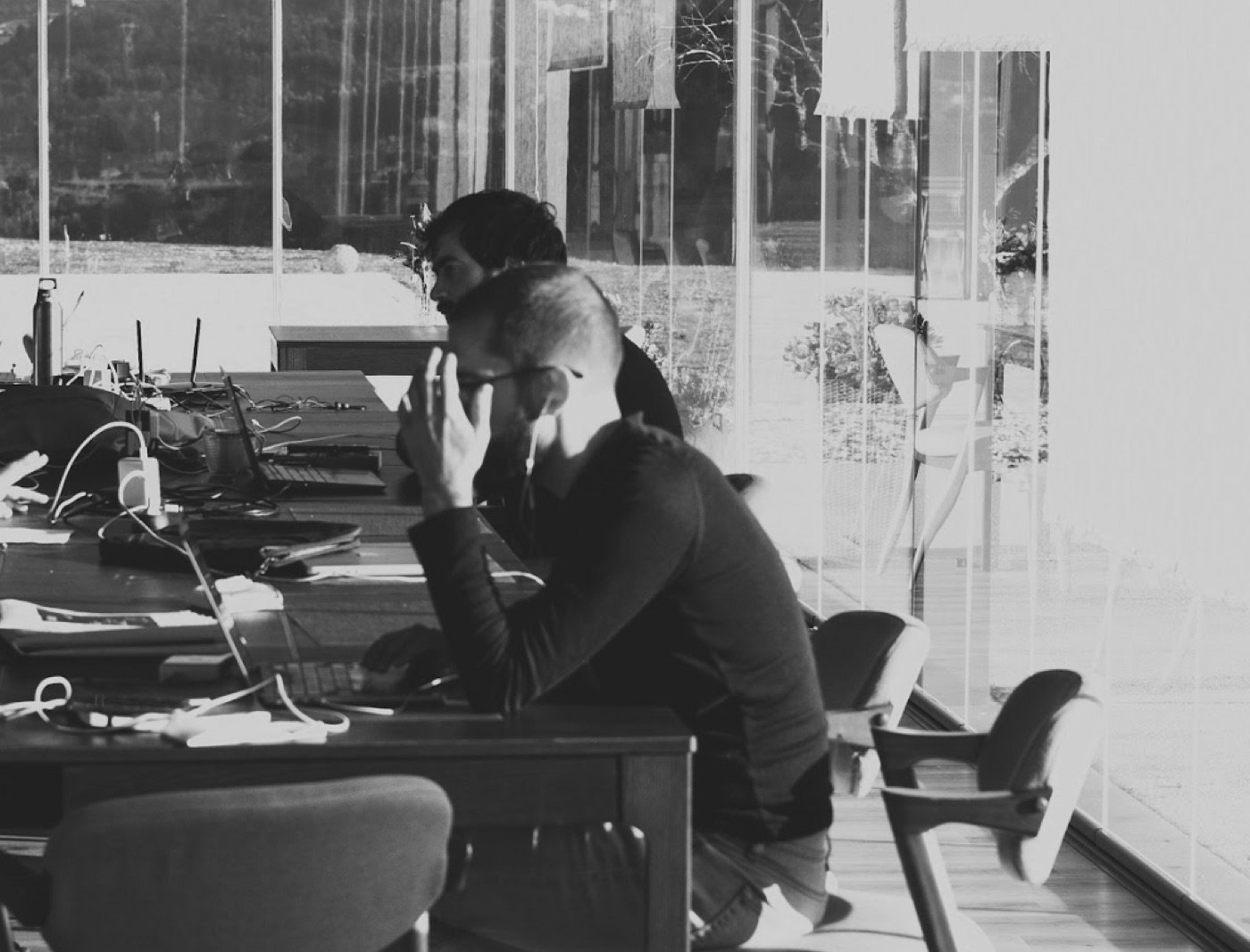 Two Whitesmith team members working at laptops at a long shared desk.